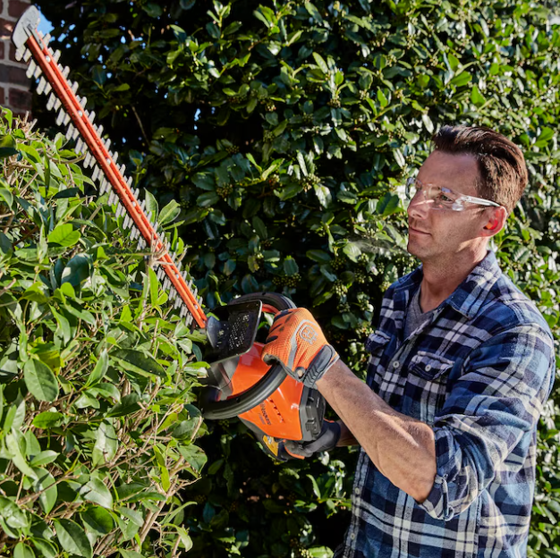 Husqvarna battery powered hedge trimmer shaping a hedge